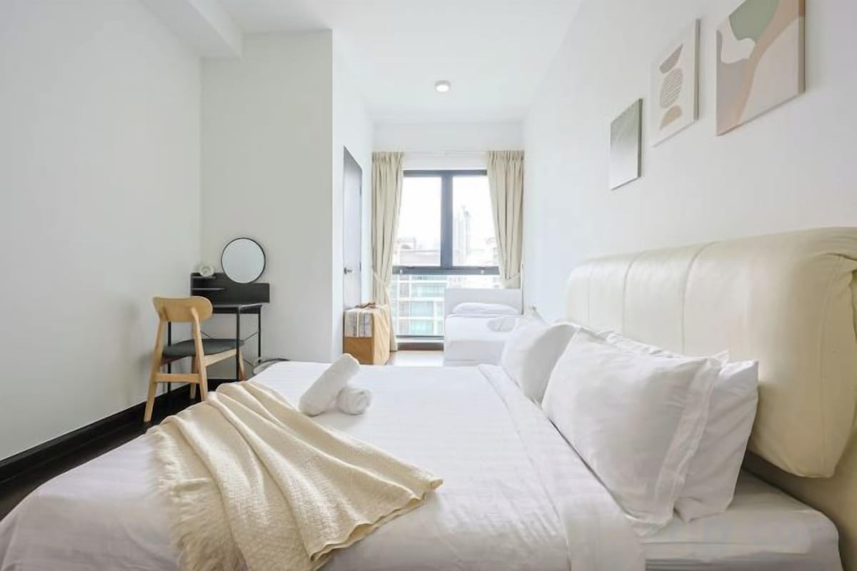 A hotel room with a bed, a desk, a chair, and a window with curtains.
