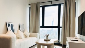 A modern living room with a sofa, a coffee table, and a view of a cityscape through large windows. - Staycation V Residence - Sunway Velocity (Kuala Lumpur)