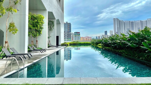 A modern hotel with a pool, lounge chairs, and a view of the city skyline. - Staycation V Residence - Sunway Velocity (Kuala Lumpur)