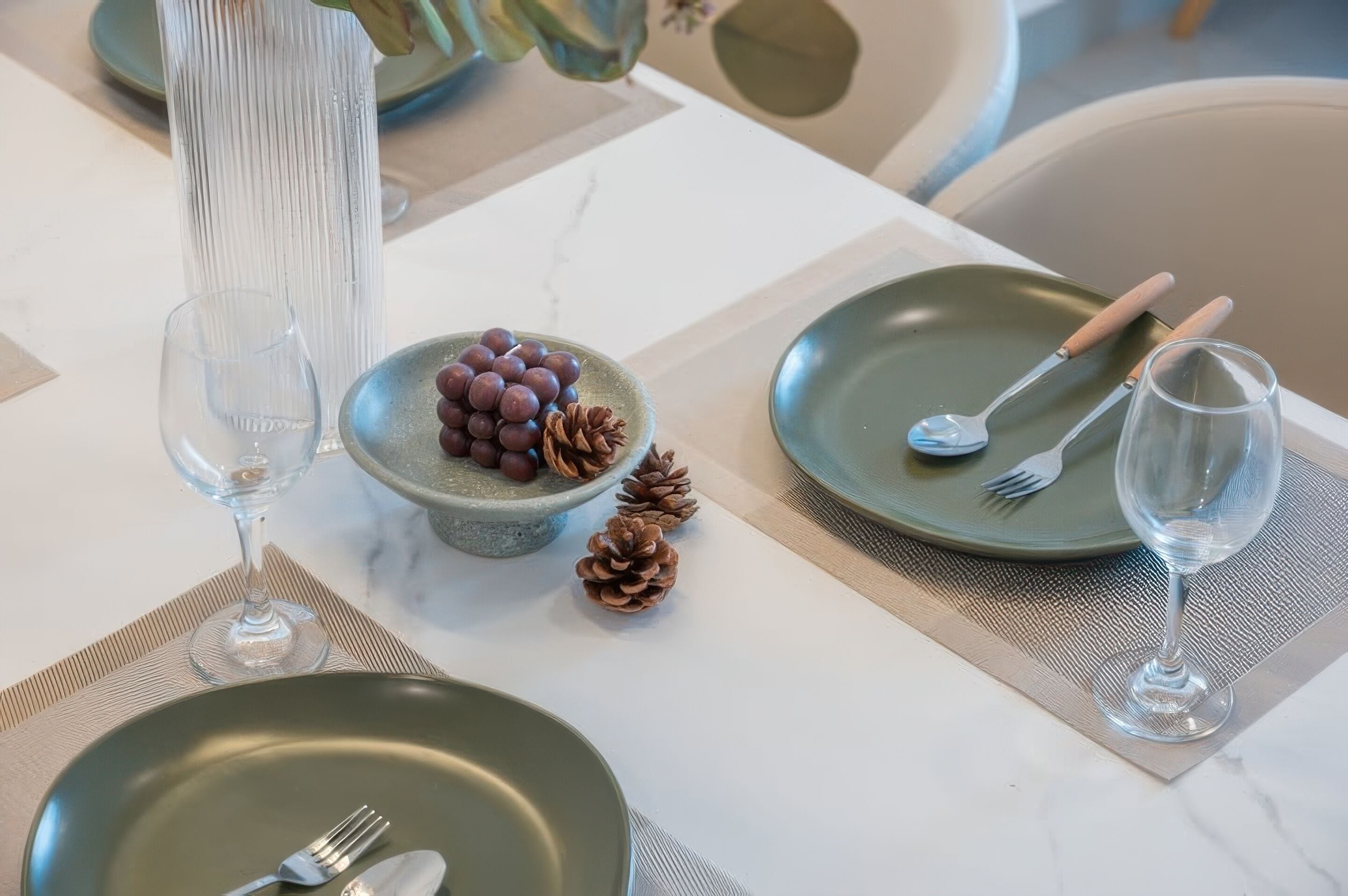 Una mesa con un bol de uvas, un vaso de agua y un plato con un tenedor y una cuchara.