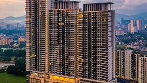 Un edificio residencial alto con varios pisos, ventanas grandes y una terraza en la azotea.