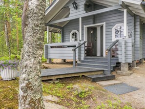 A wooden house with a porch, steps leading to the entrance, and a potted plant nearby.