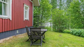 En rød bygning med et vindue og borde med stole i gården.