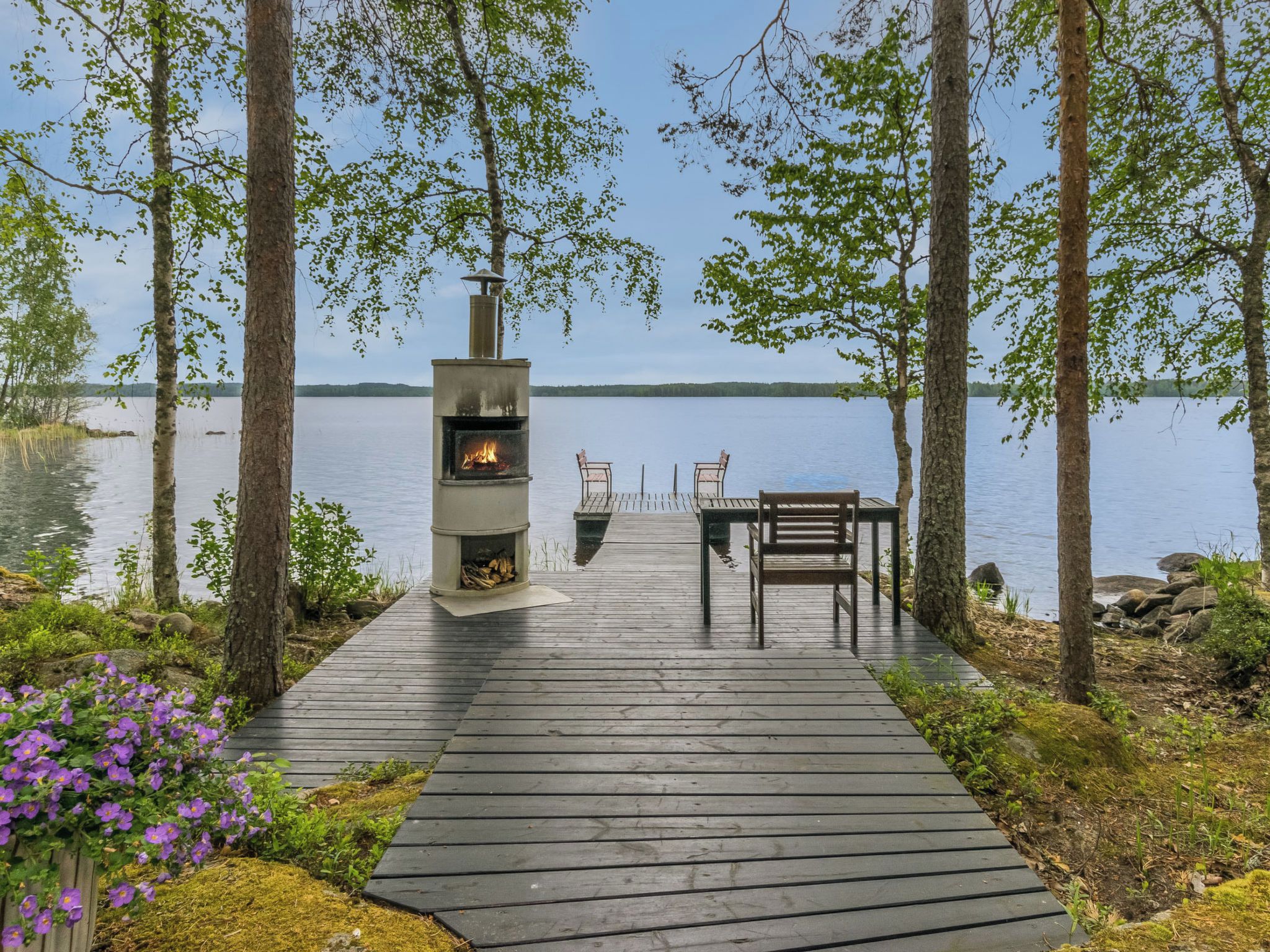 Une terrasse en bois menant à un foyer avec vue sur un lac.
