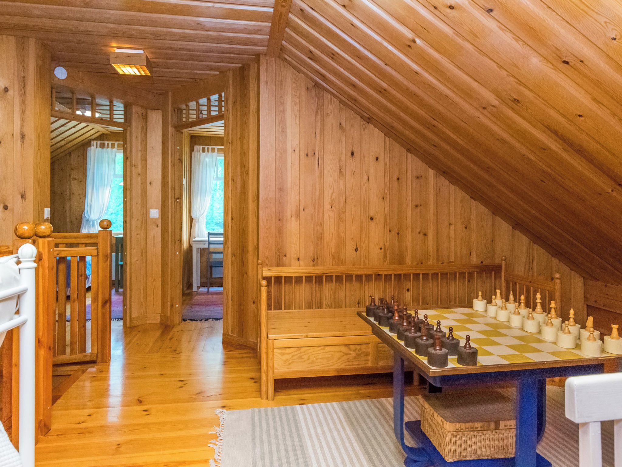 Un intérieur en bois avec un grand échiquier et un banc.