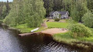 Un chalet au bord du lac, doté d’un quai, et entouré d’une forêt dense.