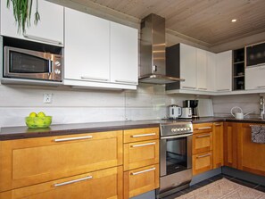 A modern kitchen with wooden cabinets, stainless steel appliances, and a built-in oven. - Aurinkoranta by Interhome (Ikaalinen)