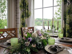 Une table à manger dressée avec des assiettes, des verres et un centre de table composé de fleurs.