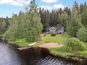 Un chalet au bord du lac, avec un quai et une cour gazonnée.