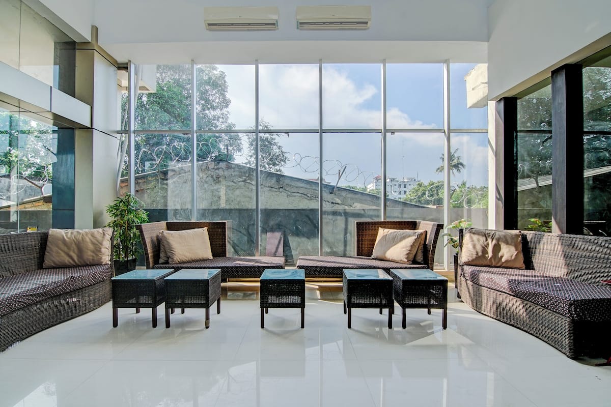 A spacious indoor area with large windows, wicker furniture, and a view of a hilly landscape.