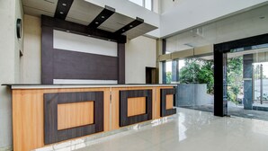 A modern reception area with a wooden counter and a large window. - Townhouse Oak Pekanbaru near Mall Pekanbaru formerly Hotel Grand Sahara (Pekanbaru)