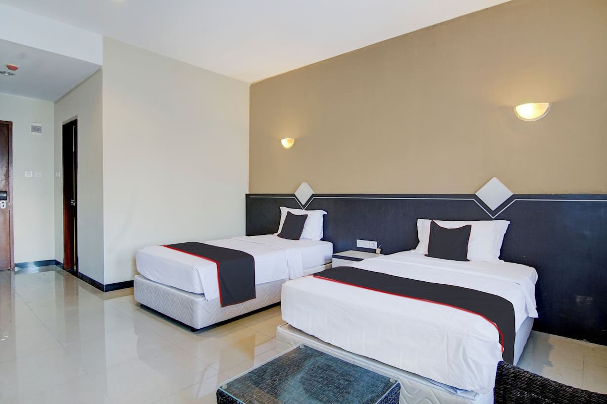 A hotel room with two beds, a dark headboard, and a light-colored wall.