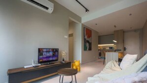 A modern living room with a flat-screen TV, a wooden coffee table, a yellow bear-shaped chair, and a sofa. - Residensi Majestic Maxim Condo (Kuala Lumpur)