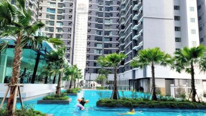 A swimming pool surrounded by tall residential buildings, palm trees, and greenery. - Residensi Majestic Maxim Condo (Kuala Lumpur)