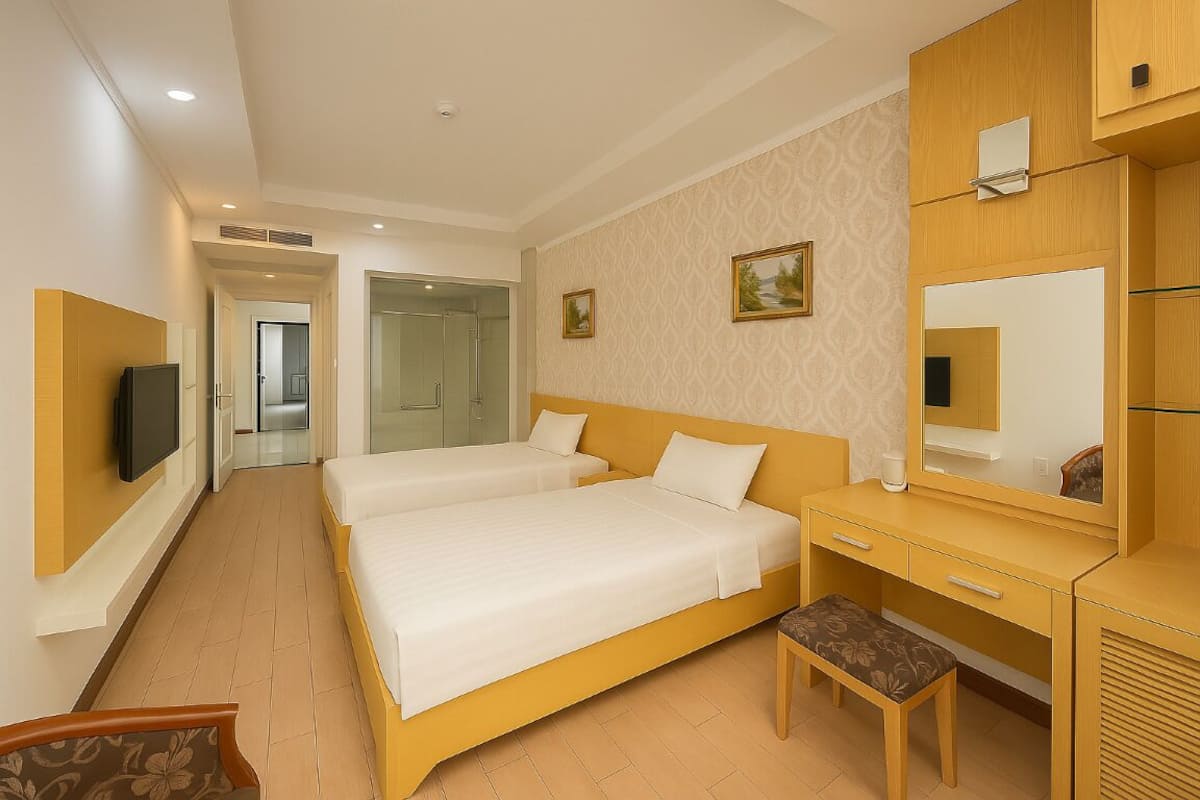 A hotel room with two beds, a desk, a chair, a television, and a mirror.