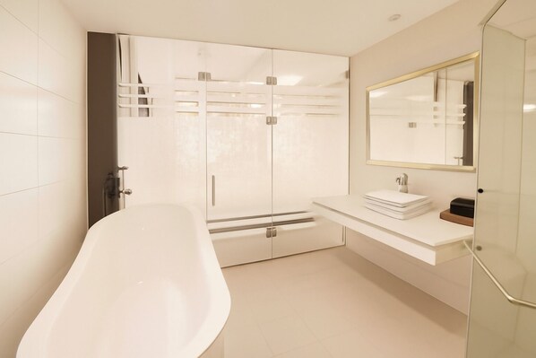 Une salle de bain moderne avec une baignoire sur pieds, une douche à parois de verre et un meuble-lavabo avec un miroir.