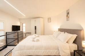 A bedroom with a bed, a TV, a desk, and a chair.