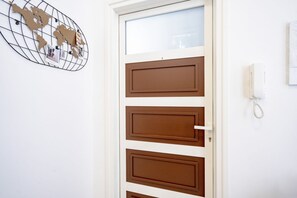 Una porta con pannello marrone, una mappa del mondo decorativa sulla parete e un telefono appeso al muro.