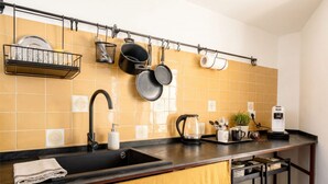 A kitchen with a black countertop, a sink, a coffee maker, and hanging pots. - Casa di Lu - Modern Soul (Bari)
