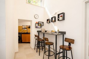 Un corridoio stretto conduce a una cucina con zona pranzo, caratterizzata da un tavolo nero e quattro sedie di legno.