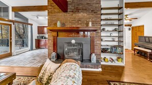 A living room with a fireplace, wooden beams, a bookshelf, and a sofa. - Bearberry Suite @Cooperstown Lodge-3mi to CDP+Pool (Cooperstown)