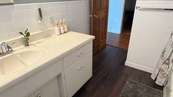 A bathroom with a white sink, wooden cabinet, and a door leading to another room.