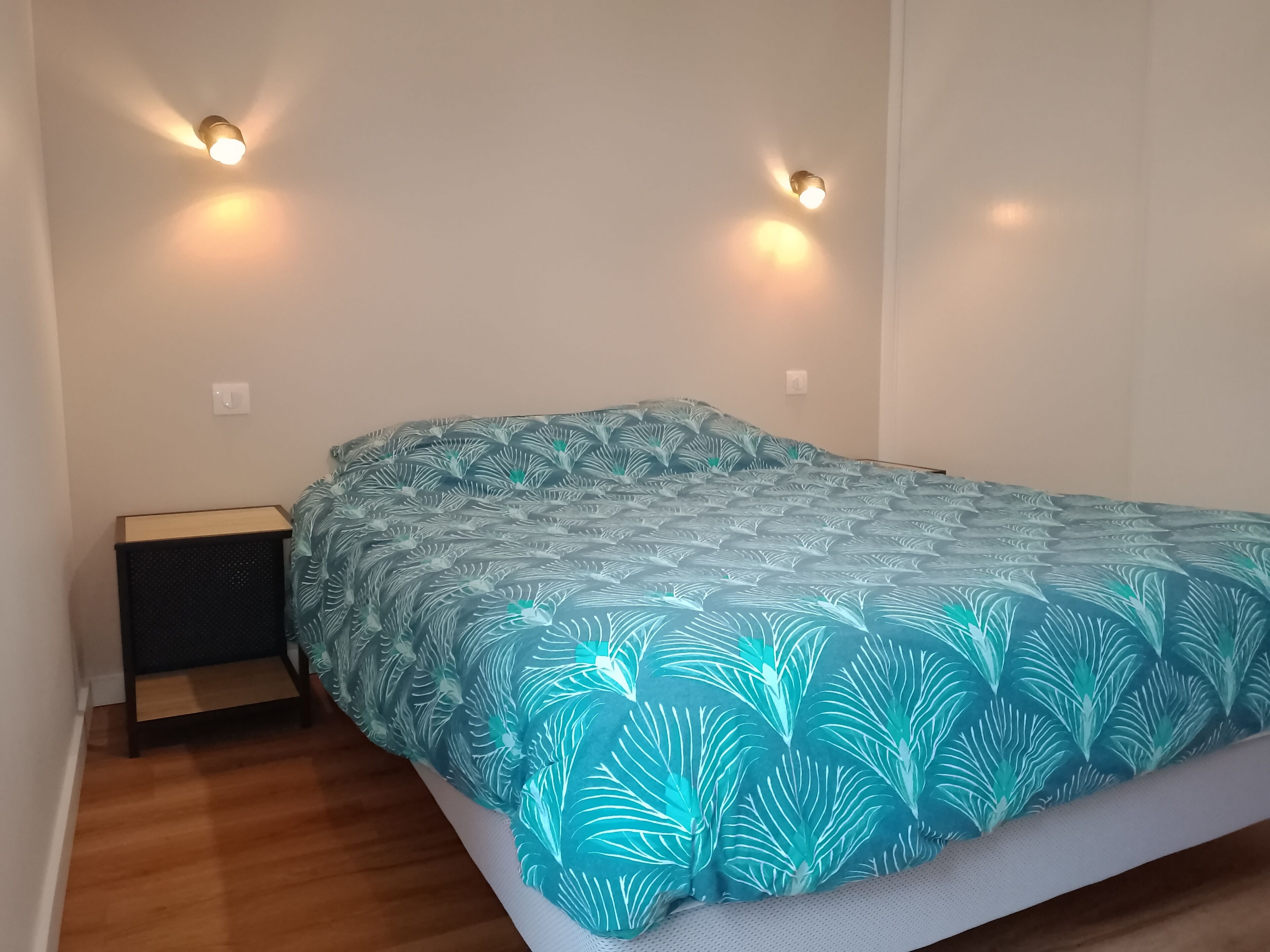 Ein Schlafzimmer mit einem Bett, zwei Wandlampen, einem Nachttisch und Holzboden.