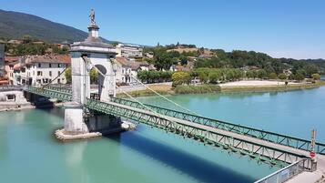 A bridge with a statue on top, connecting two land masses over a river.