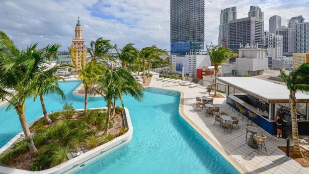 A rooftop pool with palm trees, a bar area, and a city skyline in the background. - Chic 2/2 Condo with City views (Miami)