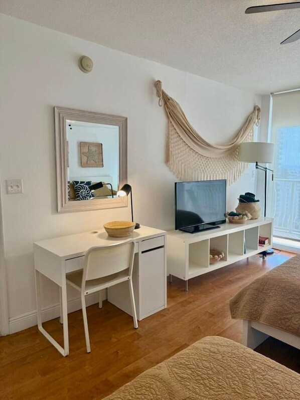 A room with a white desk, chair, and TV, a hammock, and a large window. - Bohemian apartment in Brickell (Miami)