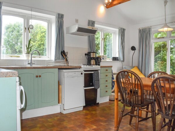 A kitchen with a dining area, large windows, and a view of greenery. - 3 bedroom accommodation in Happisburgh (Happisburgh)