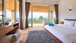 Ein modernes Schlafzimmer mit einem großen Bett, einem Schreibtisch und Meerblick.