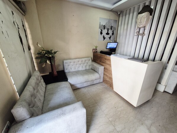 A reception area with a sofa, a reception desk, a computer monitor, and a wall-mounted camera. - Aryan Address (Guwahati)