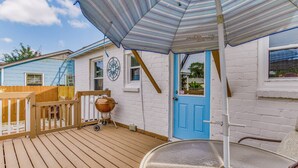Eine Holzterrasse mit Grill und einer blauen Tür.