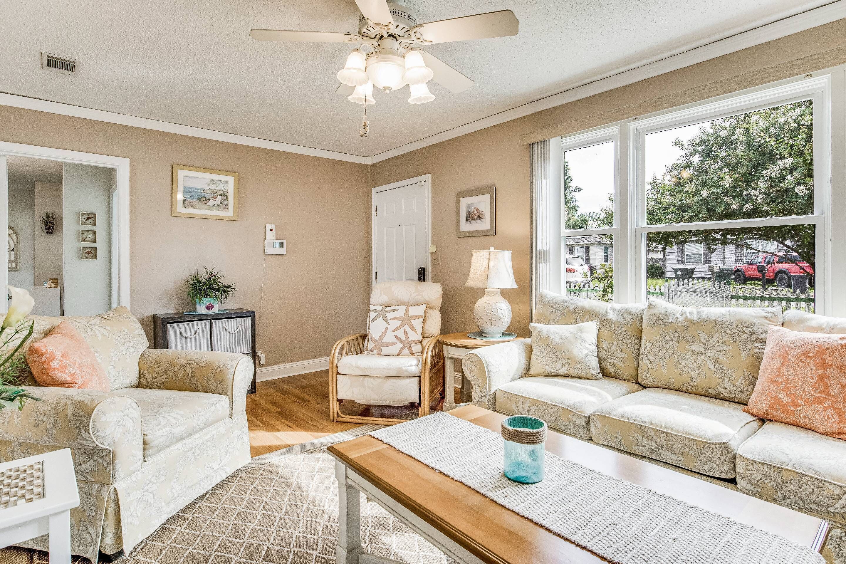 A cozy living room with a sofa, armchairs, a coffee table, and a ceiling fan.