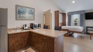 A modern hotel room with a kitchenette, a bed, a TV, and a painting on the wall. - Surestay Plus Hotel By Best Western Elizabethtown Hershey (Elizabethtown)