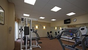 Een fitnessruimte met cardio-apparatuur, gewichten en een televisie aan de muur.
