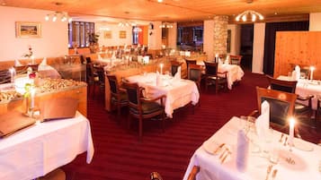 Un restaurante con varias mesas dispuestas para comer, techo de madera y pared de piedra.