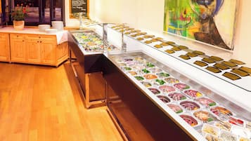 Ein reichhaltiges Buffet mit verschiedenen Speisen, eine Holztresen und ein großes, abstraktes Gemälde an der Wand.