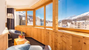 Habitación con paneles de madera y un amplio ventanal con vistas a un paisaje montañoso nevado.
