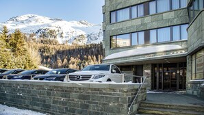 A hotel with a stone facade, a snow-covered entrance, and a mountain backdrop. - TOP Hotel San Gian St. Moritz (St. Moritz)