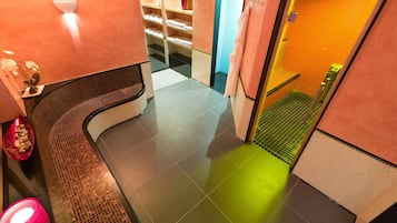 Un vestíbulo de hotel con un banco curvo, un mostrador de recepción y una escalera que lleva a un nivel superior.