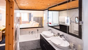 A modern bathroom with two sinks, a large mirror, and a wooden ceiling. - TOP Hotel San Gian St. Moritz (St. Moritz)