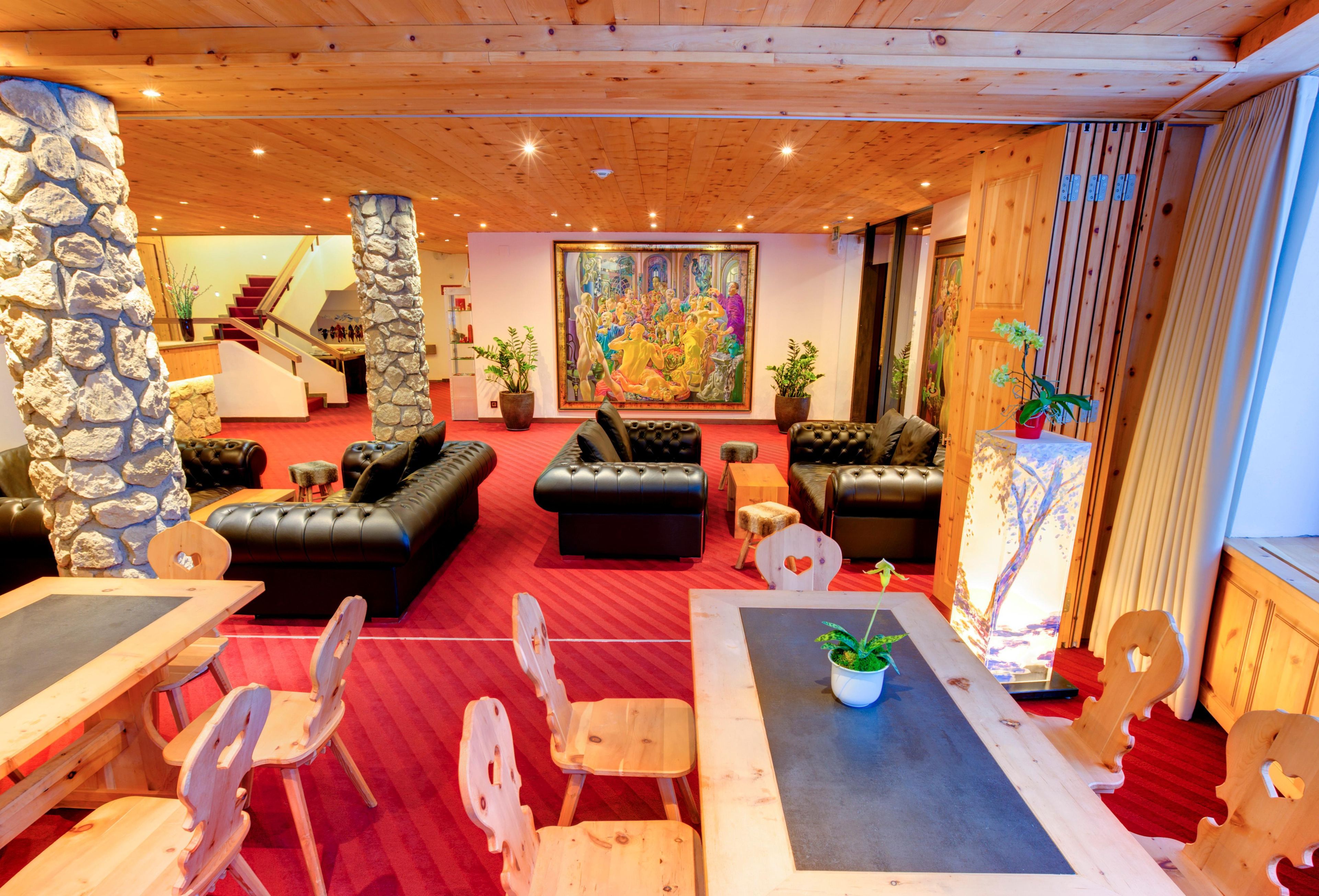 Eine Hotelhalle mit rotem Teppich, Holzmöbeln, einer Treppe und einem großen Gemälde.