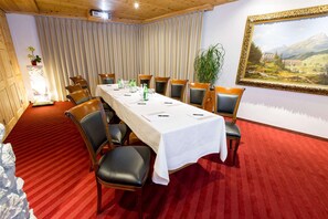 A conference room with a long table, chairs, a red carpet, a painting, and a plant. - TOP Hotel San Gian St. Moritz (St. Moritz)