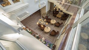 A spacious, multi-level interior with a central seating area, large windows, and a staircase. - Ratonda Centrum Hotel (Vilnius)