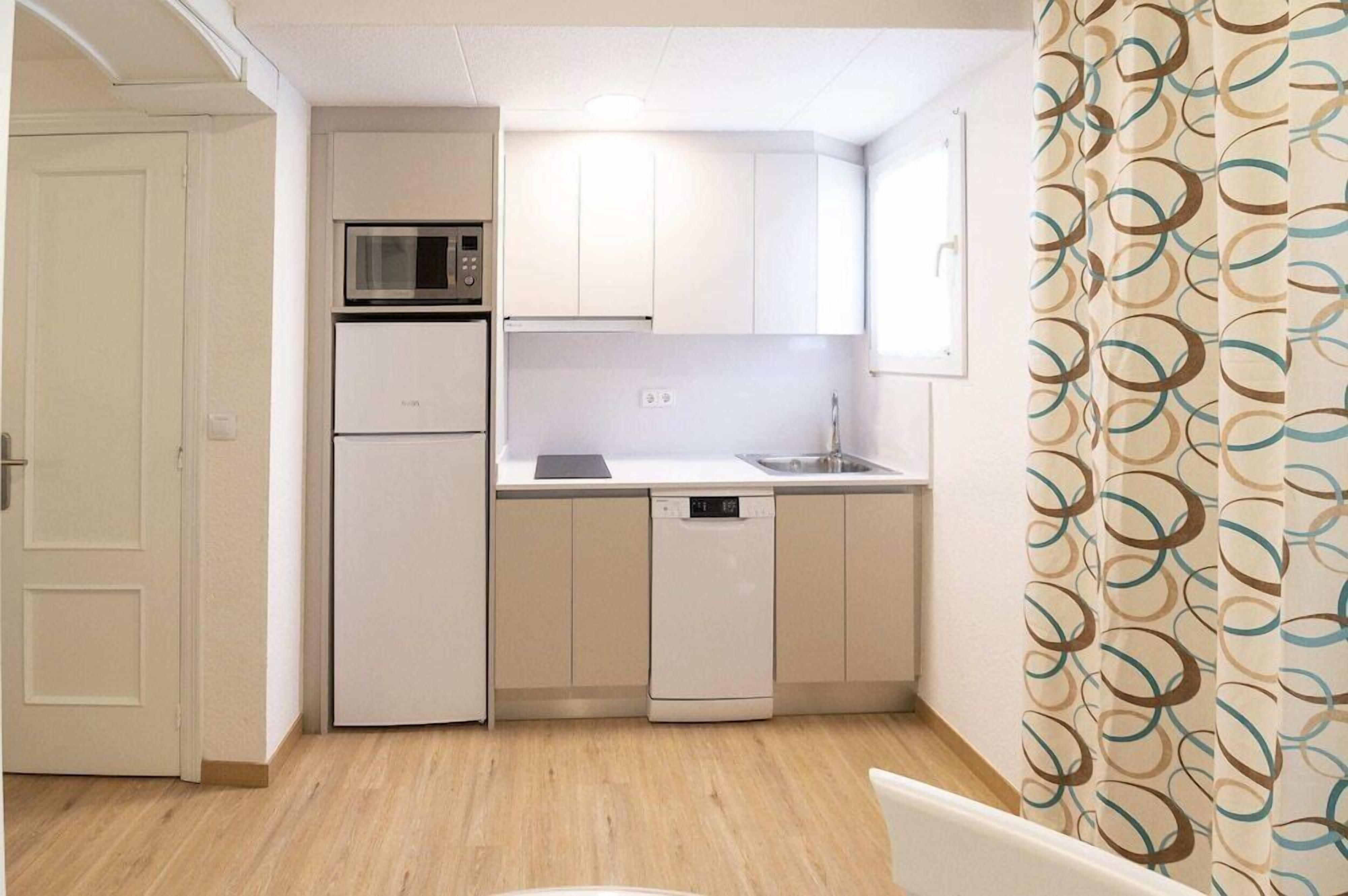A compact kitchen with white cabinets, a microwave, a dishwasher, and a sink.