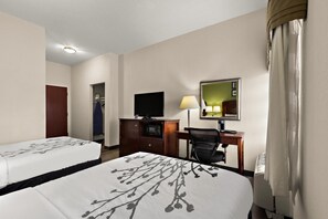 Habitació d'hotel amb dos llits, un escriptori amb un ordinador, una televisió i un mirall.