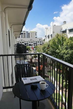 A balcony with a table, a chair, a newspaper, and a cup of coffee. - Heritage Cairns (Cairns)