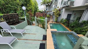 Zona de piscina en la azotea con sillones de descanso, un jacuzzi y abundante vegetación.